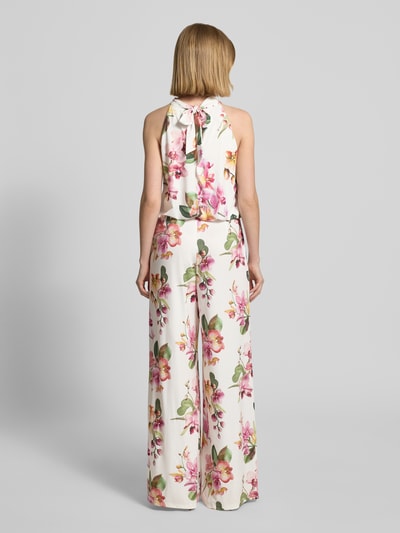 Modelka kobieca nosi Regular Fit Jumpsuit mit floralem Allover-Print von V by Vera Mont, białe tło, wielokolorowe kwiaty, bez rękawów, wycięcie na plecach, zamek kryty w szwie, krój regular fit, Szerokość w rozmiarze 36: 36 cm, długość tyłu w rozmiarze 36: 147 cm, długość całkowita w rozmiarze 36: 132 cm, długość wewnętrzna nogawki w rozmiarze 36: 81 cm, pełny widok sylwetki z tyłu.