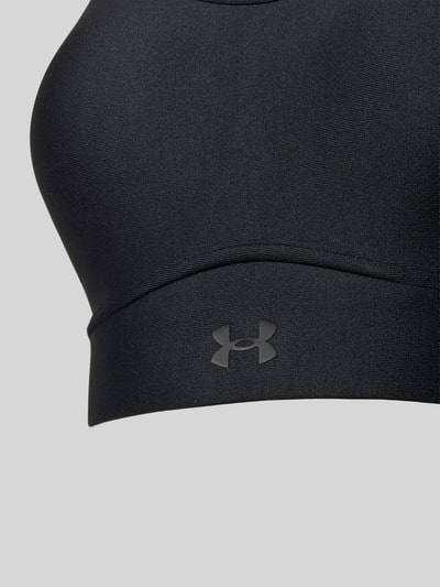 Frauenmodel trägt Regular Fit SportBH mit Logo-Print Modell 'Infinity' von Under Armour aus elastischem Material-Mix, Nahaufnahme Oberkörper.