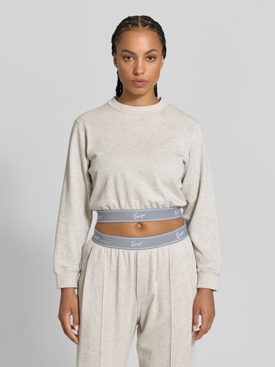 Frauenmodel trägt Cropped Sweatshirt mit Logo-Stitching von Kenzo in Beige, reine Baumwolle, elastische Abschlüsse, Rundhalsausschnitt, Ganzkörperansicht von vorne.