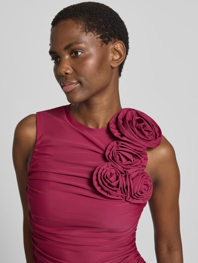 Frauenmodel trägt Cocktailkleid mit floralen Applikationen Modell 'DONA' von YAS in kräftigem Pink mit Satintextur, Nahaufnahme Oberkörper.