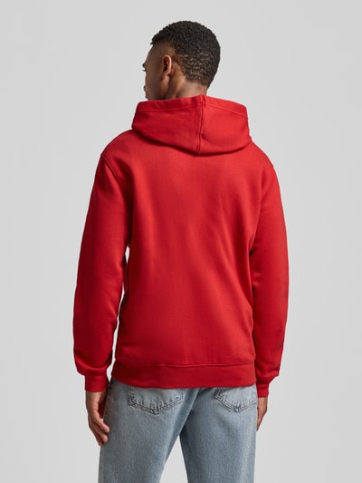 Männermodel trägt rote Sweatjacke mit Logo und Känguru-Tasche von GAP, Baumwoll-Mix, Regular-Fit, Ganzkörperansicht Rückansicht.
