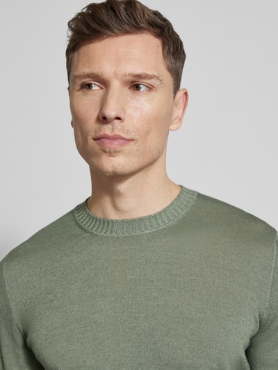 Männermodel trägt Strickpullover aus reiner Schurwolle von GRAN SASSO in Grün mit Rundhalsausschnitt, Nahaufnahme Oberkörper.