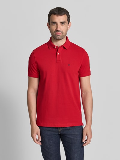 Męski model nosi Regular Fit Poloshirt aus Baumwoll-Mix von Tommy Hilfiger, intensywnie czerwony, gładka faktura, Ganzkörperansicht von vorne.