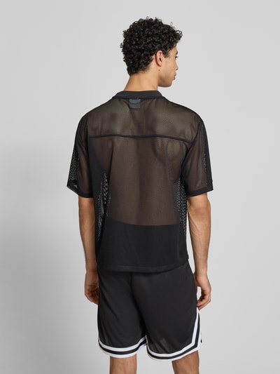 Männermodel trägt Oversized T-Shirt mit Logo-Print von KARL KANI aus schwarzem Mesh, Oversized-Fit, Rundhalsausschnitt, Rückenlänge 66 cm, Ganzkörperansicht Rückansicht.