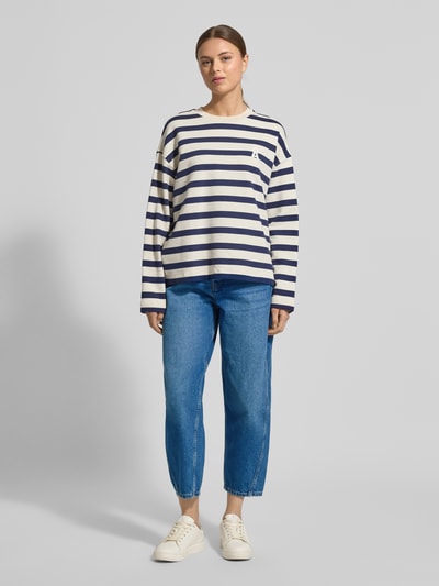 Frauenmodel trägt High Waist Barrel Jeans aus reiner Baumwolle Modell 'BAARLY' von Armedangels, Denim-Optik, Barrel Fit, Ankle-Länge, 5-Pocket-Design, Knopf und verdeckter Reißverschluss, Label-Patch, Nieten, Gürtelschlaufen, Material reine Baumwolle, Ganzkörperansicht von vorne.
