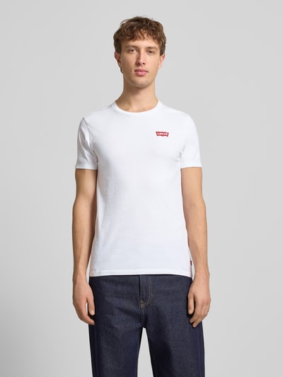 Männermodel trägt T-Shirt mit Label-Print im 2er-Pack von Levi's®, reine Baumwolle, Slim-Fit, Weiß, Gerippter Rundhalsausschnitt, Ganzkörperansicht von vorne.