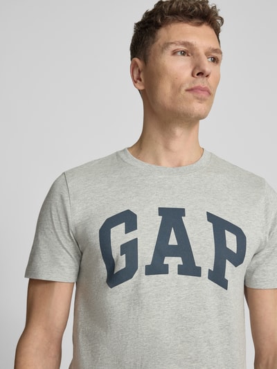 Männermodel trägt T-Shirt mit Logo und Rundhalsausschnitt von GAP in Grau, Reine Baumwolle, Regular-Fit, Logo, Nahaufnahme Oberkörper.