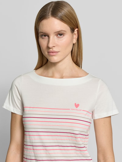 Vrouwenmodel draagt Regular Fit T-shirt uit zuiver biologisch katoen van Tom Tailor met all-over gestreept motief, labelprint, hartjesprint, boothals, korte mouw, zachte textuur, dames t-shirtlook, voorkant bovenlichaam close-up.