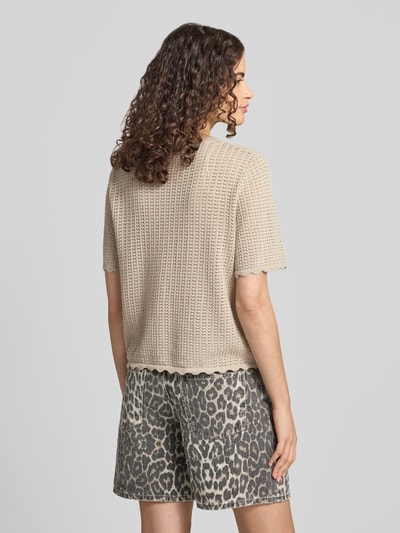Frauenmodel trägt Regular Fit Strickjacke aus reiner Baumwolle Modell 'SCOUT' von PIECES in Beige, grobe Strickstruktur, Ganzkörperansicht Rückansicht.