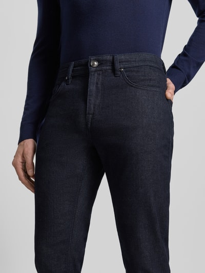 Männermodel trägt Straight Fit Jeans mit 5-Pocket-Design Modell 'Fortress' von JOOP! Collection aus dunkelblauem Baumwoll-Mix mit Stretch-Anteil, Nahaufnahme Oberkörper.
