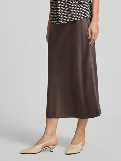 Vrouwenmodel draagt licht uitlopende midi-rok met elastische band van s.Oliver BLACK LABEL in bruin, detailopname onderlichaam.