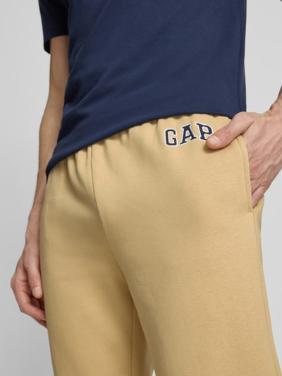 Mężczyznę model nosi Sweatpants mit elastischem Bund od GAP, bawełniany miks, krój regular fit, tylna kieszeń, beż, zbliżenie na biodra.