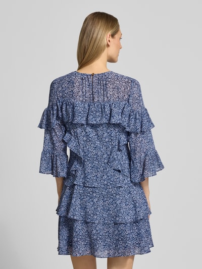 Frauenmodel trägt Minikleid mit Volants von MICHAEL Michael Kors in A-Linie, Allover-Look, Rundhalsausschnitt, Rückenlänge 86 cm, Größe S, Brustweite 44 cm, Ärmellänge 32 cm, Blautöne, florale Musterung, luftige strukturierte Textur, Ganzkörperansicht Rückansicht.