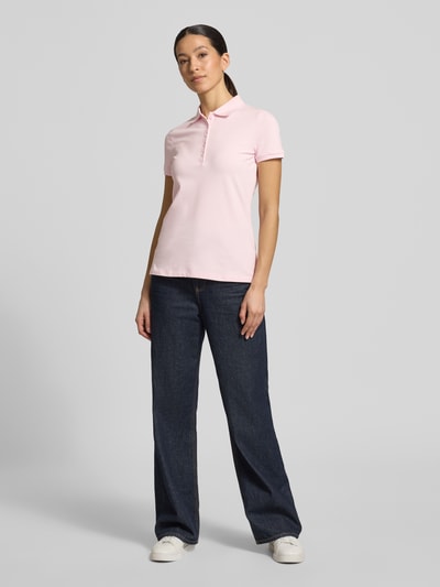 Frauenmodel trägt Slim Fit Poloshirt mit Knopfleiste von Christian Berg Woman, Baumwoll-Elasthan-Mix, Seitenschlitze, rosa, Ganzkörperansicht von vorne. Rückenlänge bei Größe S: 62 cm.