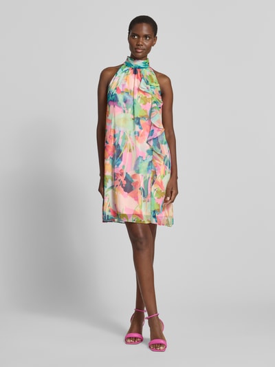 Frauenmodel trägt Cocktailkleid mit Stehkragen und Volants von Adrianna Papell, bunte A-Linie, florale Muster, Ganzkörperansicht von vorne.