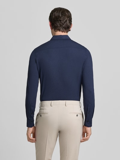 Męski model nosi Slim Fit Business-Hemd mit Knopfleiste od CRUNA, materiał ze stretchem, kołnierz kent, długość tyłu w rozmiarze 50: 65 cm, szerokość ramion w rozmiarze 50: 43 cm, długość rękawa w rozmiarze 50: 65 cm, granatowy, widok całego ciała z tyłu.
