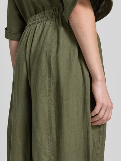 Kobiece model prezentuje Leinenhose in verkürzter Passform mit elastischem Bund von Christian Berg Woman, zielony len, szeroka nogawka, gładka tekstura, szerokość w rozmiarze 36: 38 cm, długość nogawki wewnętrznej 64 cm, detal tylnej części, ujęcie z tyłu