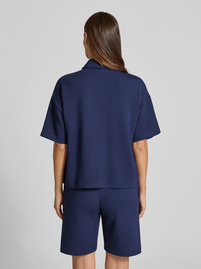 Männermodel trägt Jacke mit Umlegekragen von Christian Berg Woman, granatowy, prosty krój, elastyczny materiał, krótkie rękawy, naszyte kieszenie, widok całej sylwetki z tyłu.