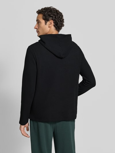 Männermodel trägt schwarzes Relaxed Fit Sweatshirt aus Baumwoll-Mix Modell 'Waffle LS' von BOSS, strukturierte Oberfläche, Ganzkörperansicht Rückansicht, Herren Hoodie von BOSS.