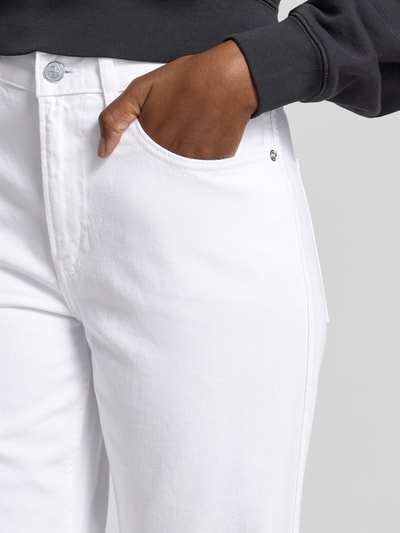 Frauenmodel trägt Flared Fit Jeans im 5-Pocket-Design von Anine Bing, weiß, strukturierte Baumwolle, silberner Knopf, Nahaufnahme Oberkörper.