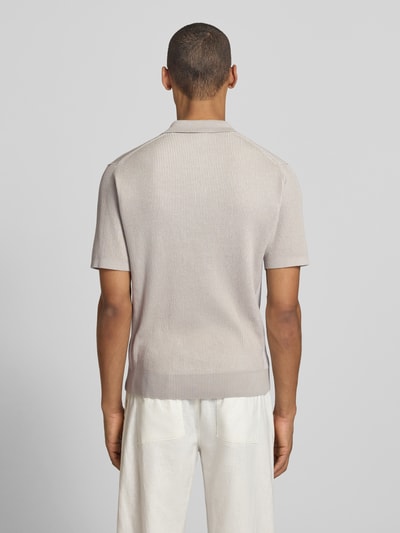 Männermodel trägt Regular Fit Poloshirt aus reiner Baumwolle Modell 'ARAVOLO' von BOSS Orange in Strickoptik, Rückansicht Ganzkörperansicht.