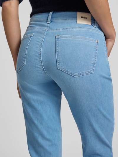 Kobiece modelka nosi Slim Fit Jeans mit Eingrifftaschen Modell 'SHAKIRA' von Brax, mieszanka bawełny i lyocellu, niebieska, wpuszczane kieszenie, krój slim fit, szerokość w rozmiarze 36: 37 cm, długość wewnętrzna nogawki w rozmiarze 36: 70 cm, ujęcie z tyłu