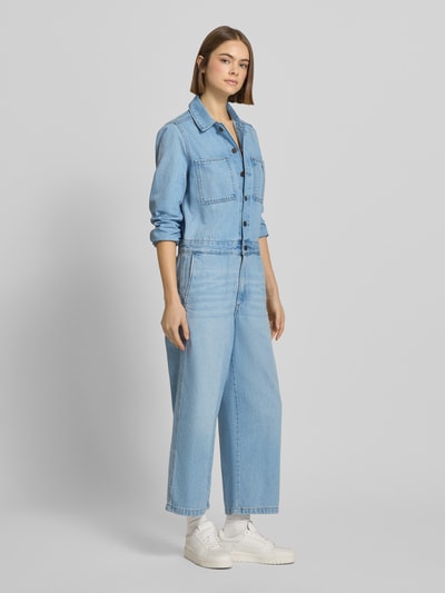 Vrouwenmodel draagt Regular Fit Jumpsuit in Denim-Optik model 'Iconic' van Levi's®, blauwe katoen, lange mouwen, borstzakken, volledige voorkant weergave.
