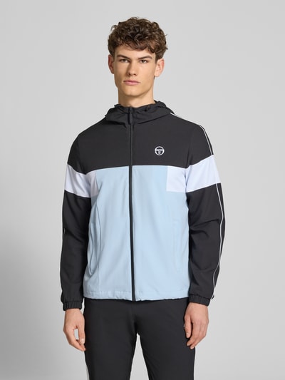 Męski model nosi Regular Fit Jacke mit Logo-Stitching Modell 'Caspio' od SERGIO TACCHINI, kolor czarny, biały, jasnoniebieski, materiał elastyczny, kaptur z troczkiem, zamek, kieszenie, elastyczne mankiety, krój regular fit, widok całej sylwetki z przodu.