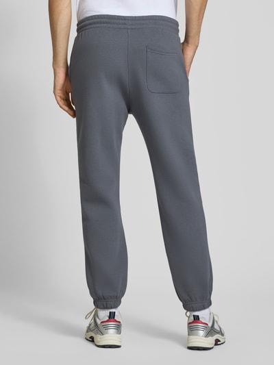 Männermodel trägt Straight Fit Sweatpants aus Baumwoll-Mix Modell 'Kane' von JACK & JONES in Grau mit Gesäßtasche und elastischem Bund, Ganzkörperansicht Rückansicht.