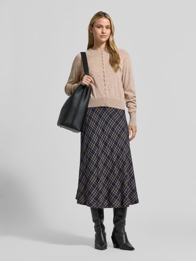 Frauenmodel trägt Regular Fit Strickjacke aus reiner Wolle von Jake*s Collection in Beige, kombiniert mit kariertem Rock und Stiefeln, Ganzkörperansicht von vorne.