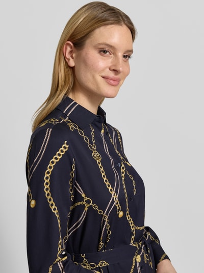 Frauenmodel trägt Hemdblusenkleid aus Viskose mit Bindegürtel von Gant in Dunkelblau mit goldfarbenem Kettenmuster, Nahaufnahme Oberkörper, taillierter Schnitt, Hemdblusenkragen, Knopfleiste, reine Viskose, Midikleid.