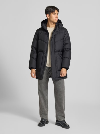 Männermodel trägt Regular Fit Steppmantel mit Kapuze von Marc O'Polo DENIM in Schwarz, glatte Oberfläche, gerade Formen, Ganzkörperansicht von vorne.