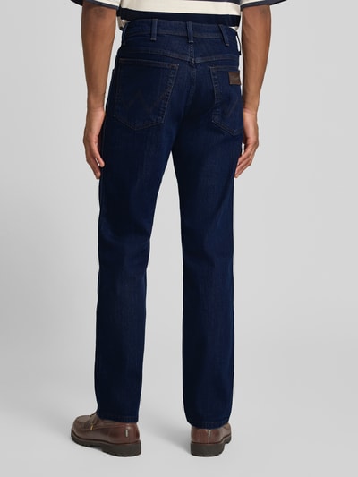 Männermodel trägt Straight Fit Jeans im 5-Pocket-Design Modell 'Texas' von Wrangler aus Baumwoll-Mix mit Stretch-Anteil, Gerader-Schnitt, Dunkelblau, Detailreiche Struktur, Knopf-Reißverschluss, Bundweite 41 cm, Innenbeinlänge 81 cm, Ganzkörperansicht Rückansicht.