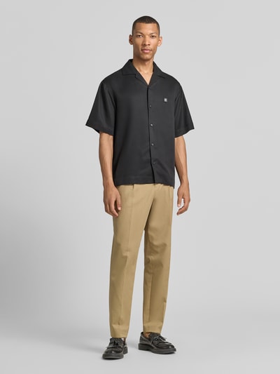Männermodel trägt Relaxed Fit Freizeithemd aus reinem Lyocell Modell 'ESPINO' von HUGO in Schwarz, unifarben, Resortkragen, Ganzkörperansicht von vorne