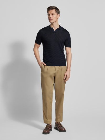 Männermodel trägt dunkelblaues Slim Fit Poloshirt mit Lyocell-Anteil von Emporio Armani, Strick-Optik, Kurzarm, Ganzkörperansicht von vorne.
