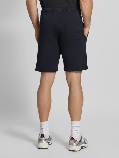 Männermodel trägt Sweatshorts mit Eingrifftaschen von Christian Berg Men in Dunkelblau, Reine Baumwolle, Regular-Fit, Label-Detail, Ganzkörperansicht Rückansicht.