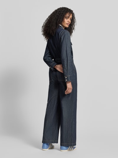 Frauenmodel trägt Jumpsuit mit kurzem Reißverschluss von Jake*s Casual in Denim-Optik mit Hemdblusenkragen, Stoffgürtel, Taillierter Schnitt, Ganzkörperansicht Rückansicht.