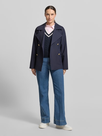 Kobiece model nosi bezrękawnik z dekoltem w serek i wyhaftowanym logo od Gant z bawełny, krój slim fit, ścieg warkoczowy, długość tyłu w rozmiarze S: 50 cm, pełen widok od przodu