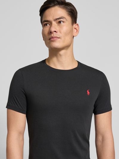 Männermodel trägt T-Shirt mit Label-Stitching von Polo Ralph Lauren, schwarze Baumwolle, Regular Fit, Nahaufnahme Oberkörper.