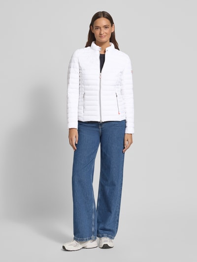 Frauenmodel trägt Steppjacke mit Zweiwege-Reißverschluss Modell 'JUDY' von Frieda & Freddies, weiß, gesteppt, Ganzkörperansicht von vorne. Slim Fit, Stehkragen, Reißverschlusstaschen, Rückenlänge 57 cm, Schulterbreite 40 cm, Brustweite 48 cm, Ärmellänge 64 cm.