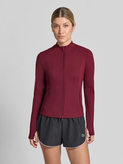 Frauenmodel trägt Slim Fit Jacke mit Zweiwege-Reißverschluss Modell 'Sense' von aim'n in Dunkelrot, glatte Textur, Ganzkörperansicht von vorne. Rückenlänge 28 cm, Schulterbreite 36 cm, Brustweite 35 cm.