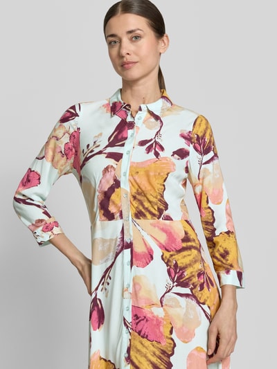 Modelka kobieca ma na sobie Hemdblusenkleid aus Viskose mit Knopfleiste Modell 'SAVANNA' od YAS, kolorowy wzór, czysta wiskoza, krój A-linii, długość maxi, guziki, całopowierzchniowy nadruk, długość tyłu w rozmiarze S: 140 cm, szerokość w rozmiarze S: 47 cm, długość rękawa w rozmiarze S: 49 cm, widok na górną część ciała z przodu.