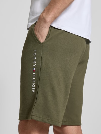 Männermodel trägt Relaxed Fit Sweatshorts aus Baumwoll-Mix von Tommy Hilfiger, Optik: Unifarben, Label-Stitching-Applikation, Nahaufnahme Oberschenkel.