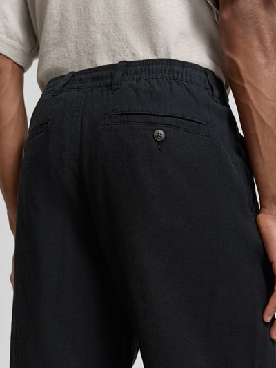 Männermodel trägt Loose Fit Leinenhose mit Tunnelzug Modell 'BRODY' von Selected Homme, efekt: jednolity kolor, krój loose fit, szlufki na pasek, tunel, zapięcie na guzik i zamek błyskawiczny, wpuszczane kieszenie, z tyłu kieszeń z guzikiem, wykończenie materiału: cieniowana przędza, materiał: mieszanka bawełny ekologicznej i lnu, detailaufnahme tylnej części
