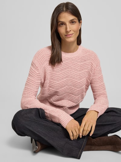 Frauenmodel trägt Strickpullover mit gerippten Abschlüssen von Guess in Rosa, lockerer Schnitt, gestrickte Textur, Ganzkörperansicht von vorne.