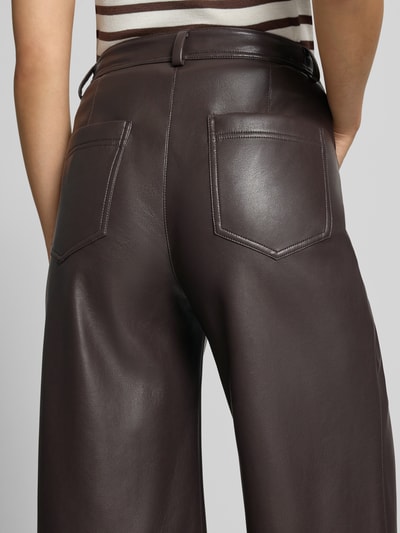 Frauenmodel trägt Straight Fit Hose mit Eingrifftaschen von Marc Cain in dunklem Braun, Leder-Optik, Gesäßtaschen, Nahaufnahme Rückansicht.