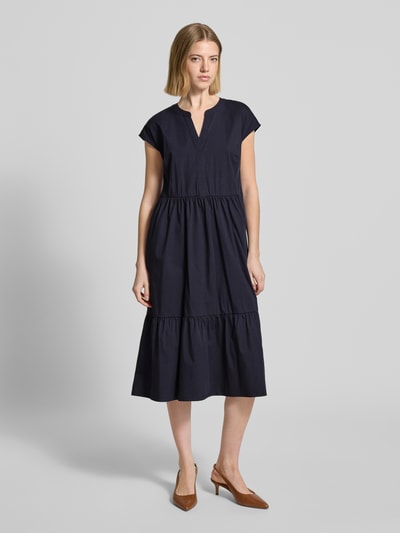 Modelka nosi Knielanges Kleid im Stufen-Look mit V-Ausschnitt von ROBE LÉGÈRE, mieszanka bawełny z dodatkiem streczu, linia a, długość do kolan, efekt stopniowania, dekolt w serek, krótkie rękawy, długość tyłu w rozmiarze 36: 104 cm, szerokość w rozmiarze 36: 46 cm, kolor granatowy; całkowite ujęcie z przodu.