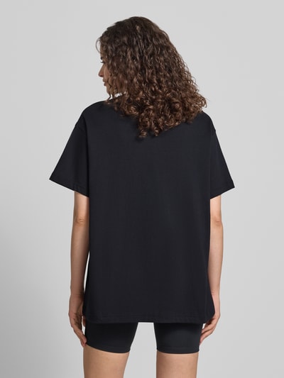 Modelka nosi Damski t-shirt z Logo i okrągłym dekoltem od Nike w czarnym kolorze, krój oversized, bawełna, Długość tyłu 68 cm, całkowity widok z tyłu.