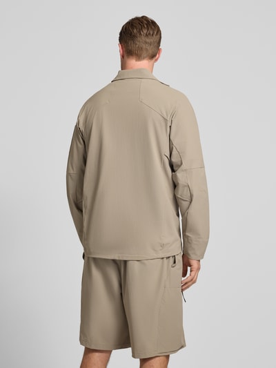 Männermodel trägt Regular Fit Trainingsjacke mit Label Patch Modell 'OW_GLOBE' von BOSS Green in Optik: Unifarben, Stehkragen, Zweiwege-Reißverschluss, Langarm, elastischer Ärmelabschluss, Reißverschlusstaschen, Ärmeltasche, beige, strukturierte glatte Oberfläche, Ganzkörperansicht Rückansicht.