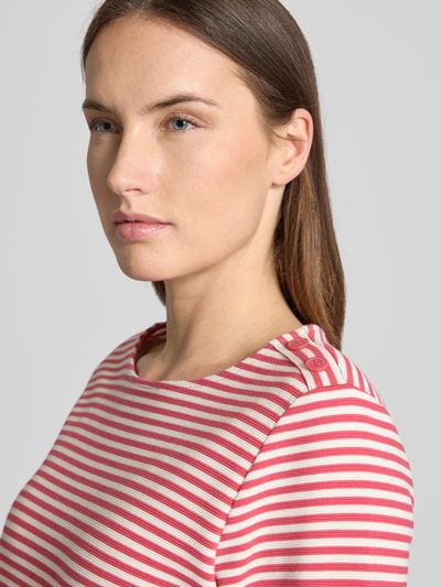 Frauenmodel trägt Regular Fit 3/4-Shirt aus Bio-Baumwoll-Mix von Tom Tailor, gestreift in Rosa-Weiß, Knöpfe am Rundhals, Nahaufnahme Oberkörper.